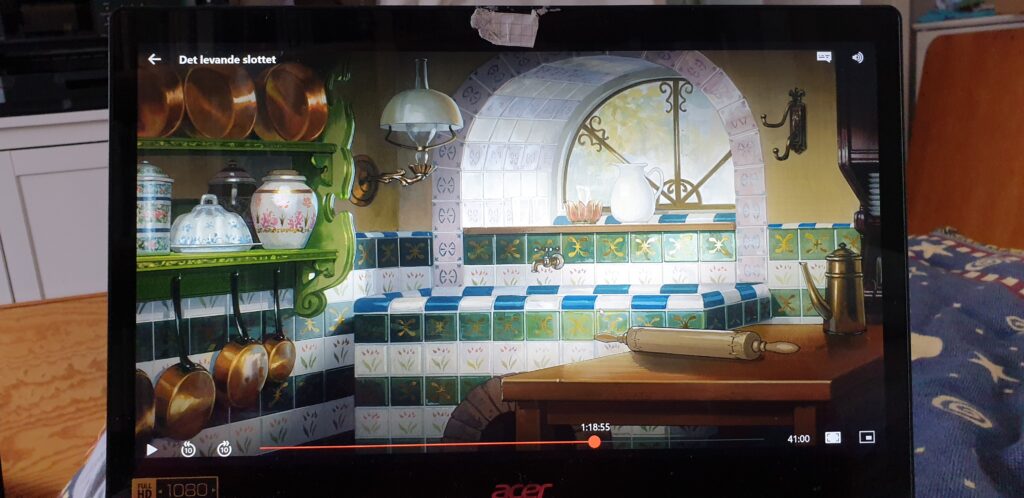 The wet corner now has a tiled sink, and the tiles are green or white with gold decorations. The green shelf have become more ornate and holds porcelaine with elaborate flower motifs and copper cookware. On the other side a sturdy wooden workbench holds a rolling pin and a decorated coffee pot. An ornate kerosene lamp is mounted on the wall above the sink, and the window is enforced with gilded and decorated bars.